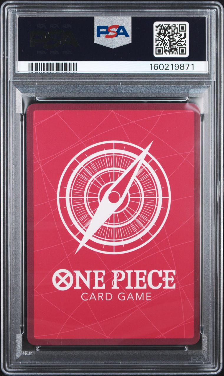 A PSA graded One Piece Card Game deck box featuring a red card face with a white compass design and text, sealed inside a clear PSA slab with a black label at the top.