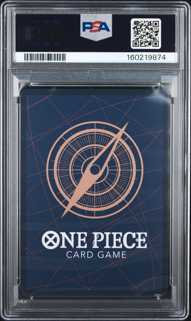 A PSA graded One Piece Card Game deck box inside a clear plastic grading case, showing a dark blue box with a compass design and white text.