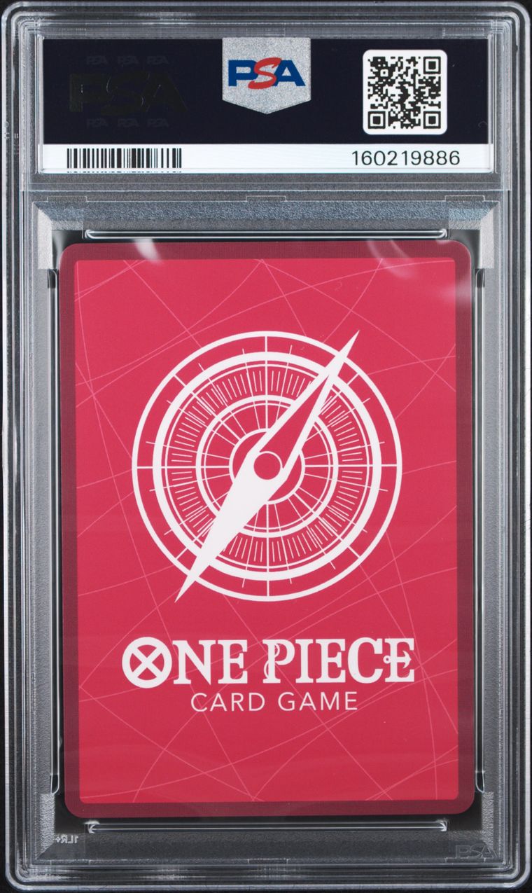 A PSA graded One Piece Card Game red backless deck box or card sleeve inside a clear plastic grading case, with the PSA label visible at the top and a red insert featuring a white compass design and the text 'ONE PIECE CARD GAME'.