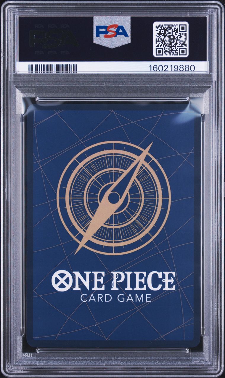 A PSA graded One Piece Card Game deck box inside a clear plastic grading case. The box is dark blue with a gold compass design and white text, and the PSA label is visible at the top.