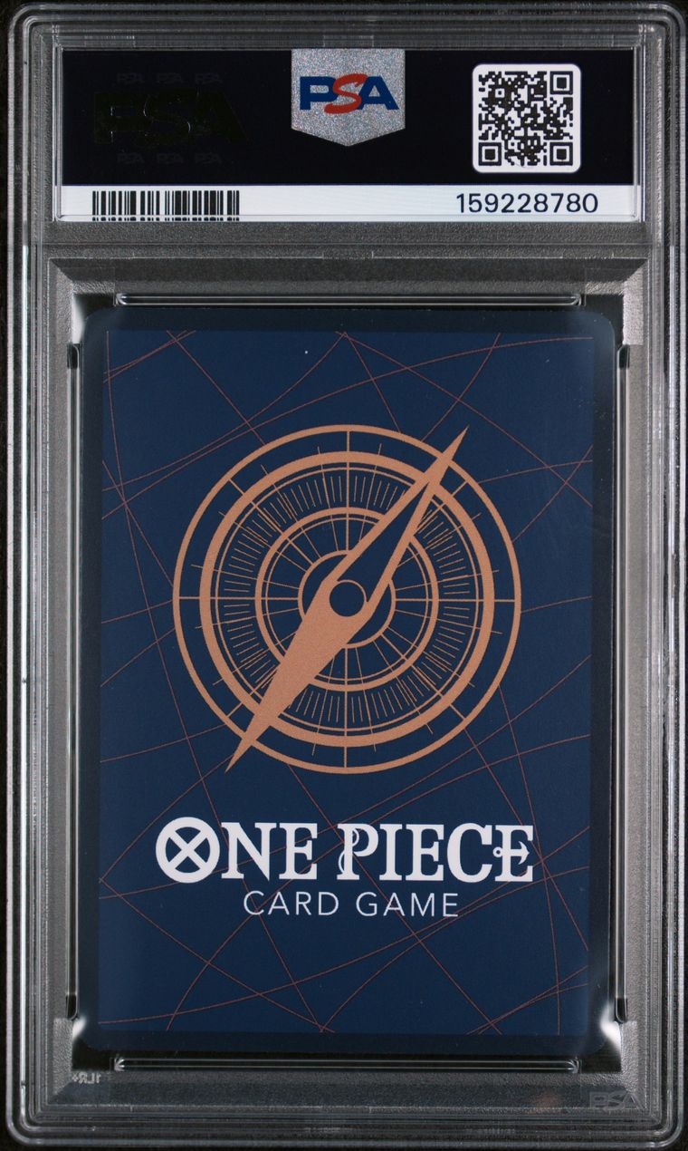 A PSA graded One Piece Card Game deck box inside a clear plastic grading case, featuring a dark blue background with a copper compass design and white One Piece branding.