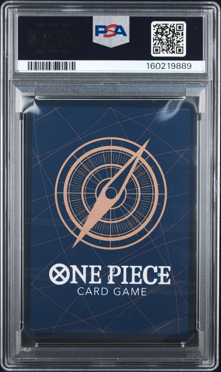 A PSA graded One Piece Card Game deck box inside a clear plastic grading case, showing a dark blue box with a gold compass design and white One Piece branding.